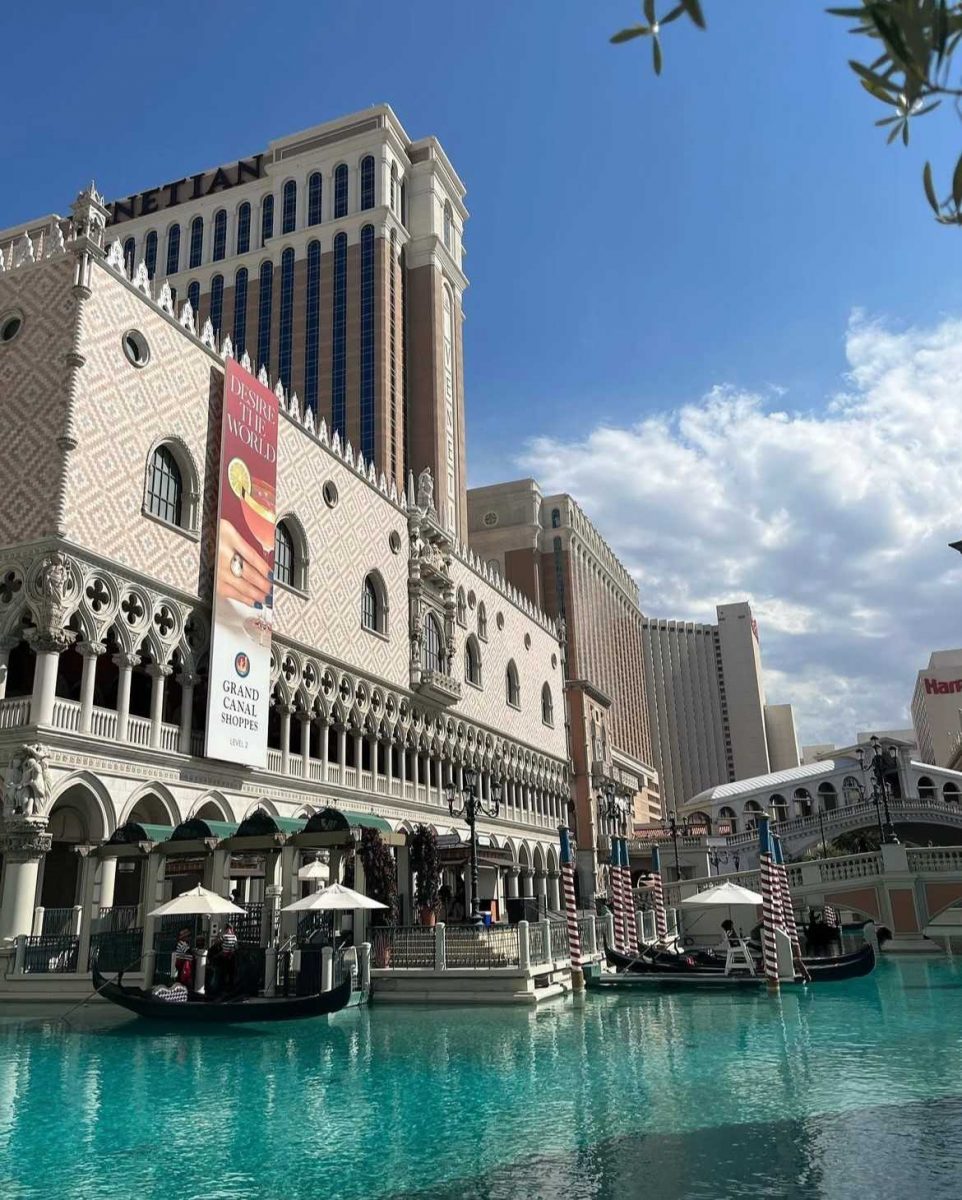 Gondolas floating on the turquoise canal at The Venetian Hotel in Las Vegas beneath a bright blue sky.